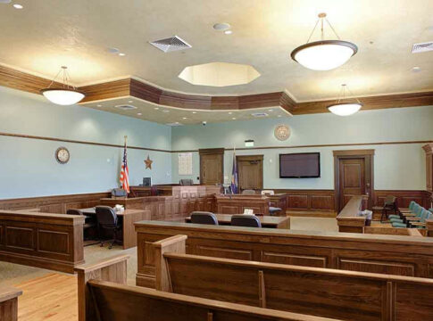 Empty courtroom with wooden benches and desks.