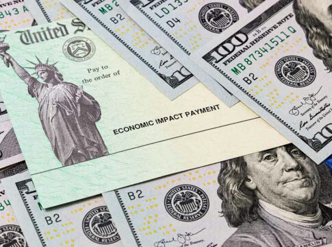 Economic Impact Payment check surrounded by hundred-dollar bills.