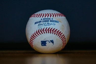 Baseball with red stitching on a wooden surface