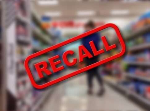 A blurred grocery store aisle with a prominent RECALL sign in red