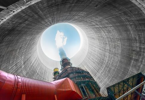 View from inside a cooling tower of a power plant, showing smoke and blue sky