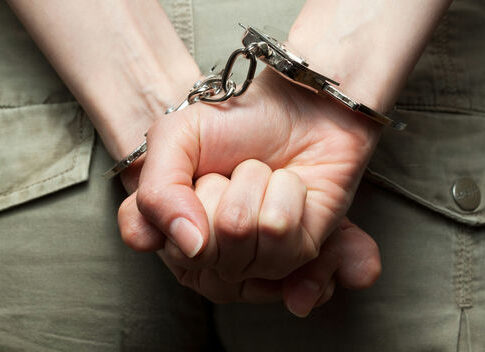 Person in handcuffs with hands behind back.